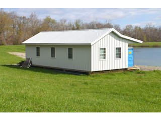 28.5+/- ACRES, a beautiful getaway featuring a well stocked 9 acre, 20+ foot deep lake stocked with bass, bluegill, and have caught large pike occasionally.  Formerly a gravel pit, this lake is bordered by groomed lawn grasses with a very large gravel beach to the lake for great swimming!!  A good sized metal building with covered porch, perfect for weekend and overnight stays.  Adjacent to the St. Joseph River with over 3,000 feet of river frontage, this property has wonderful scenic river views, where deer and turkey travel abundantly, and offers great duck and goose hunting on the lake!  
A great put-in site for river canoe and kayak trips, it offers a wonderful potential building site for year round home or private getaway!  And would also be a wonderful RV and Camper getaway spot!!  Only about a 40 minute drive from Fort Wayne, 30 minutes from Grabill, 20 minutes from Bryan, 35 minutes from Defiance, 30 minutes from Auburn! - 28.5+/- Acres with 9+/- acre Lake, Woods, Possible Building Sites