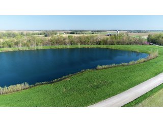 28.5+/- ACRES, a beautiful getaway featuring a well stocked 9 acre, 20+ foot deep lake stocked with bass, bluegill, and have caught large pike occasionally.  Formerly a gravel pit, this lake is bordered by groomed lawn grasses with a very large gravel beach to the lake for great swimming!!  A good sized metal building with covered porch, perfect for weekend and overnight stays.  Adjacent to the St. Joseph River with over 3,000 feet of river frontage, this property has wonderful scenic river views, where deer and turkey travel abundantly, and offers great duck and goose hunting on the lake!  
A great put-in site for river canoe and kayak trips, it offers a wonderful potential building site for year round home or private getaway!  And would also be a wonderful RV and Camper getaway spot!!  Only about a 40 minute drive from Fort Wayne, 30 minutes from Grabill, 20 minutes from Bryan, 35 minutes from Defiance, 30 minutes from Auburn! - 28.5+/- Acres with 9+/- acre Lake, Woods, Possible Building Sites
