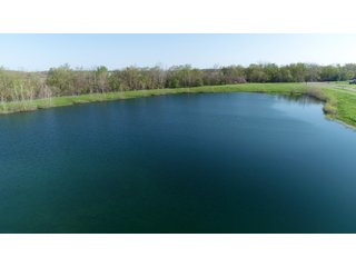 28.5+/- ACRES, a beautiful getaway featuring a well stocked 9 acre, 20+ foot deep lake stocked with bass, bluegill, and have caught large pike occasionally.  Formerly a gravel pit, this lake is bordered by groomed lawn grasses with a very large gravel beach to the lake for great swimming!!  A good sized metal building with covered porch, perfect for weekend and overnight stays.  Adjacent to the St. Joseph River with over 3,000 feet of river frontage, this property has wonderful scenic river views, where deer and turkey travel abundantly, and offers great duck and goose hunting on the lake!  
A great put-in site for river canoe and kayak trips, it offers a wonderful potential building site for year round home or private getaway!  And would also be a wonderful RV and Camper getaway spot!!  Only about a 40 minute drive from Fort Wayne, 30 minutes from Grabill, 20 minutes from Bryan, 35 minutes from Defiance, 30 minutes from Auburn! - 28.5+/- Acres with 9+/- acre Lake, Woods, Possible Building Sites