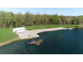 28.5+/- ACRES, a beautiful getaway featuring a well stocked 9 acre, 20+ foot deep lake stocked with bass, bluegill, and have caught large pike occasionally.  Formerly a gravel pit, this lake is bordered by groomed lawn grasses with a very large gravel beach to the lake for great swimming!!  A good sized metal building with covered porch, perfect for weekend and overnight stays.  Adjacent to the St. Joseph River with over 3,000 feet of river frontage, this property has wonderful scenic river views, where deer and turkey travel abundantly, and offers great duck and goose hunting on the lake!  
A great put-in site for river canoe and kayak trips, it offers a wonderful potential building site for year round home or private getaway!  And would also be a wonderful RV and Camper getaway spot!!  Only about a 40 minute drive from Fort Wayne, 30 minutes from Grabill, 20 minutes from Bryan, 35 minutes from Defiance, 30 minutes from Auburn! - 28.5+/- Acres with 9+/- acre Lake, Woods, Possible Building Sites